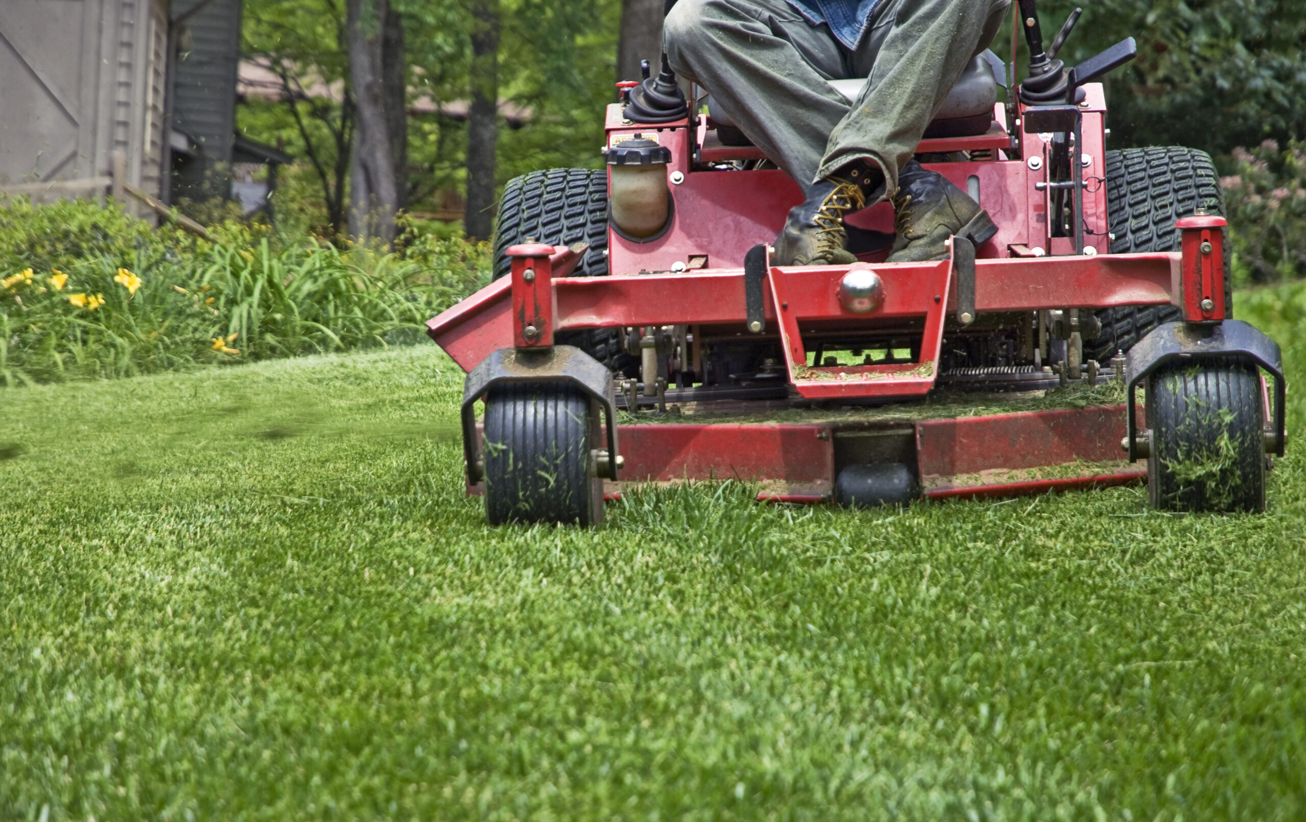 Closeup of a riding mower cutting the grass.